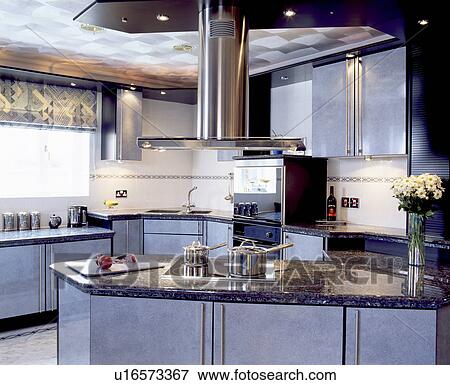 Stock Photo - Stainless steel extractor above hob in peninsular unit in modern grey kitchen. Fotosearch