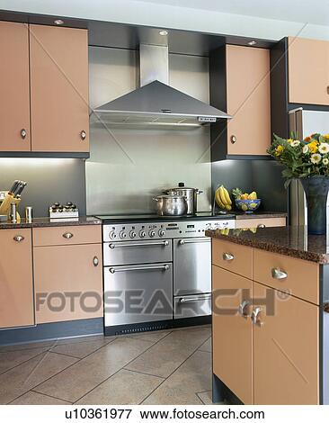 Stainless steel extractor above range oven in modern kitchen with peach fitted units View Large Photo Image Stock Photo - Stainless steel extractor above range oven in modern kitchen with peach fitted units. Fotosearch