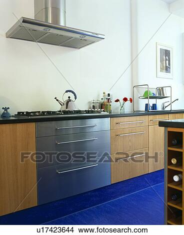 Picture - Stainless steel extractor above steel oven with Alessi kettle on hob in modern kitchen with bright blue Marmoleum flooring. Fotosearch