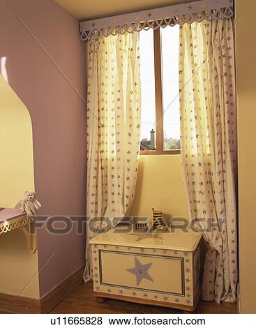 Stock Photo - Star-patterned painted chest-of-drawers in front of window with matching curtains. Fotosearch
