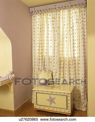 Stock Photography - Star-patterned painted chest-of-drawers in front of window with matching curtains. Fotosearch