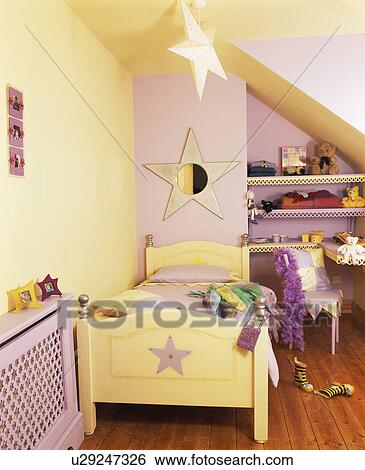 Stock Photograph - Star-themed painted wooden bed in mauve and cream child's bedroom. Fotosearch