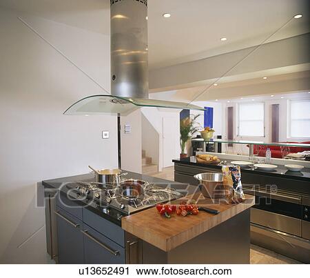 Steel and glass extractor above hob in island unit in large modern kitchen View Large Photo Image Stock Image - Steel and glass extractor above hob in island unit in large modern kitchen. Fotosearch
