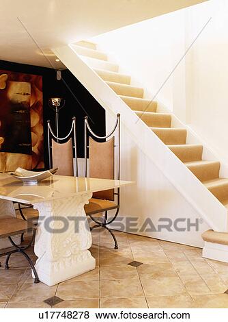 Stock Photo - Stone table and leather+metal chairs in modern country hall with open staircase. Fotosearch
