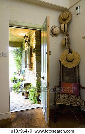 Straw hats on wall above antique chair in country hall with open front door View Large Photo Image Stock Photo - Straw hats on wall above antique chair in country hall with open front door. Fotosearch