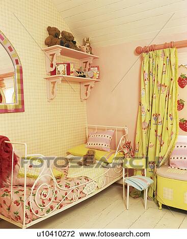 Stock Image - Strawberry-print bedlinen on metal bed in child's pink bedroom with green curtains. Fotosearch