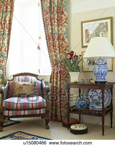 Striped armchair below window with floral curtains View Large Photo Image Stock Photograph - Striped armchair below window with floral curtains. Fotosearch