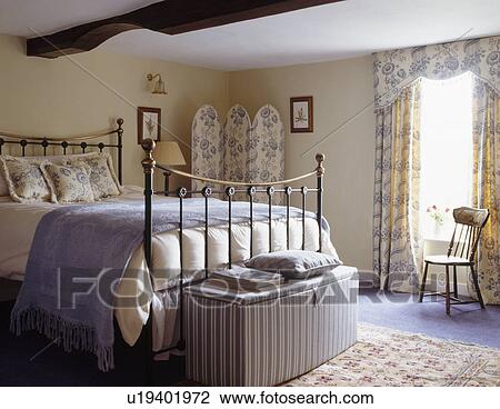 Striped ottoman below brass bed in country bedroom View Large Photo Image Stock Image - Striped ottoman below brass bed in country bedroom. Fotosearch