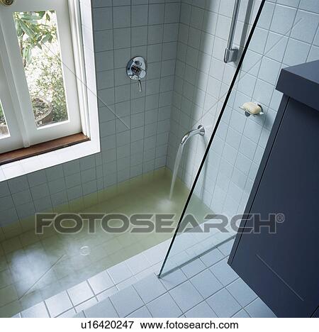 Sunken bath with glass shower screen and water pouring from tap into bath View Large Photo Image Stock Photo - Sunken bath with glass shower screen and water pouring from tap into bath. Fotosearch
