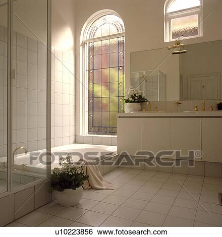 Tall arched window above step-in bath in modern white bathroom View Large Photo Image Stock Photograph - Tall arched window above step-in bath in modern white bathroom. Fotosearch