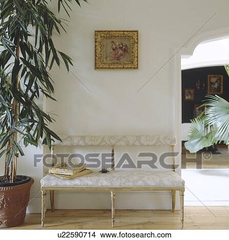 Tall houseplant beside antique upholstered settle in cream hall View Large Photo Image Picture - Tall houseplant beside antique upholstered settle in cream hall. Fotosearch