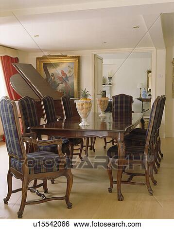 Stock Photograph - Tartain upholstered chairs and antique table in country dining room with wooden flooring. Fotosearch