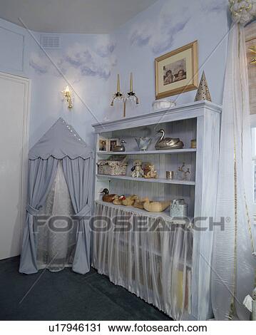 Stock Image - Tented storage and freestanding shelves in child's nursery bedroom with painted cloud effects on the walls. Fotosearch