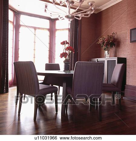 Stock Photograph - Textured terracotta wallpaper in modern dining room with mauve upholstered chairs and circular table. Fotosearch