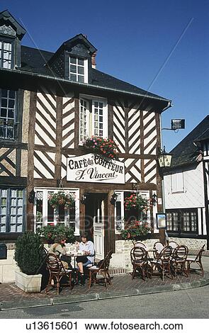 Stock Image - Tourists outside Cafe du Coiffeur, Beuvron-en-Auge, Normandy, France. Fotosearch