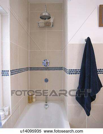 Stock Photography - Towel on peg beside shower and bath in modern modern white tiled bathrood. Fotosearch