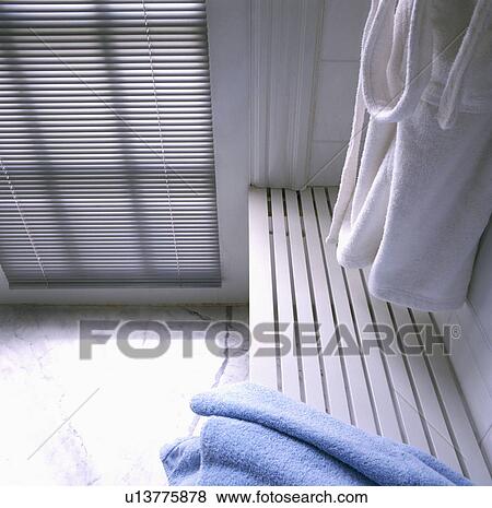 Stock Photo - Towelling bathroom and white wooden bench in modern white bathroom. Fotosearch