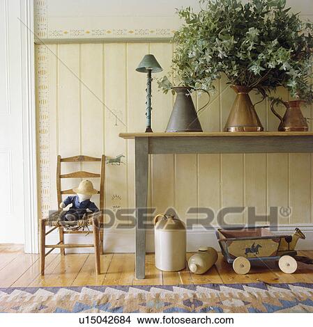 Picture - Toys on chair beside pastel blue table in dado panelled hall. Fotosearch