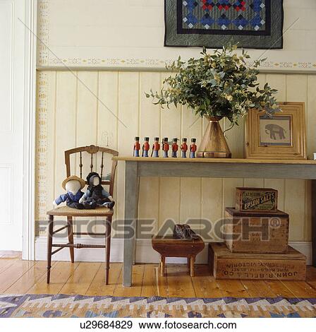 Stock Photo - Toys on chair beside pastel blue table in dado panelled hall. Fotosearch