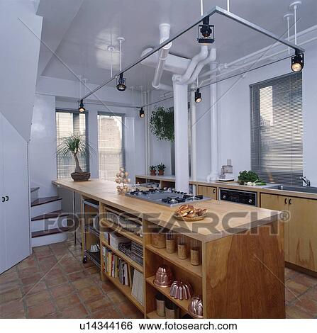 Track lighting above wooden fitted shelving unit in modern white city kitchen View Large Photo Image Stock Photograph - Track lighting above wooden fitted shelving unit in modern white city kitchen. Fotosearch