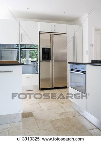 Stock Image Of Travertine Floor Tiles In Modern White Kitchen With Stock Image Travertine Floor Tiles In Modern White Kitchen With Large Stainless Steel Fridge Freezer