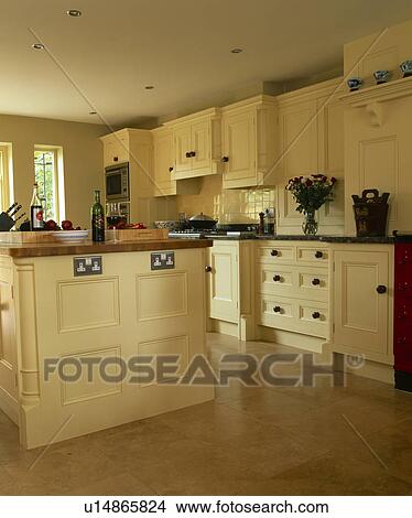 Picture - Travertine tiled floor in townhouse kitchen with cream fitted cupboards and units painted in Farrow+Ball paint. Fotosearch