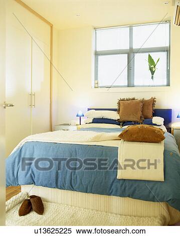 Stock Photography - Turquoise bedlinen on bed in small modern bedroom. Fotosearch