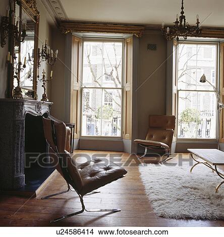 Picture - Upholstered leather and chrome chairs in living room with tall sash windows and Flokati rug on wooden floorboards. Fotosearch