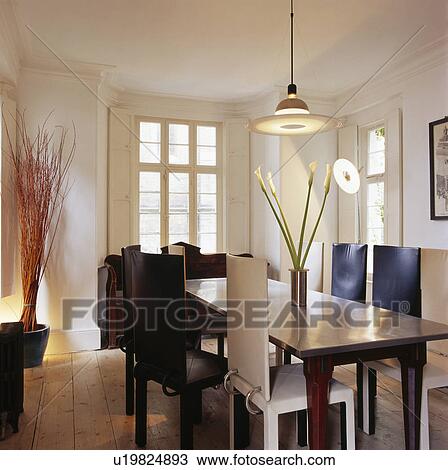 Stock Image - Upholstered leather chairs and oak table in modern white dining room. Fotosearch