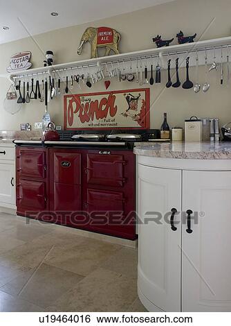 Stock Photograph - Utensils on long shelf above brown double Aga oven in modern country kitchen. Fotosearch