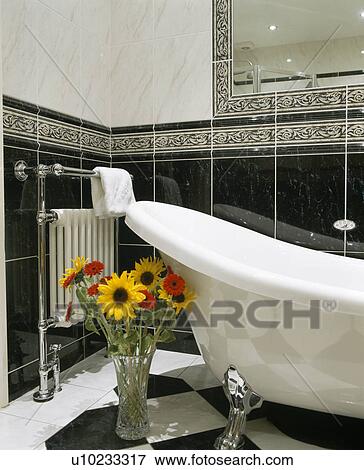 Vase of yellow daisies beside rolltop slipper bath in black tiled bathroom View Large Photo Image Stock Photo - Vase of yellow daisies beside rolltop slipper bath in black tiled bathroom. Fotosearch