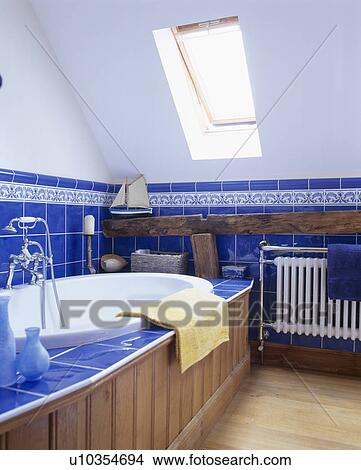 Velux window in white attic bathroom with bright blue tiles and pine-panelled bath View Large Photo Image Picture - Velux window in white attic bathroom with bright blue tiles and pine-panelled bath. Fotosearch