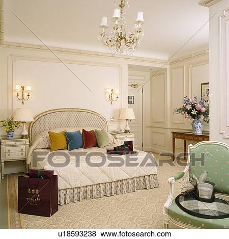 Stock Photo - Velvet cushions on bed with cream bedcover in large townhouse bedroom. Fotosearch