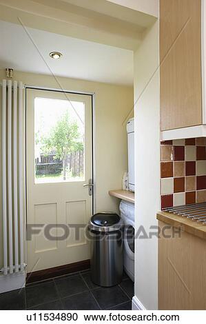 Stock Image - Vertical radiator beside half-glazed door in small utility room. Fotosearch