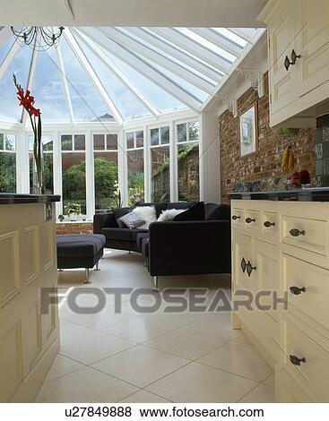 View from kitchen of white ceramic tiled floor and black sofa in modern conservatory extension View Large Photo Image Stock Photo - View from kitchen of white ceramic tiled floor and black sofa in modern conservatory extension. Fotosearch