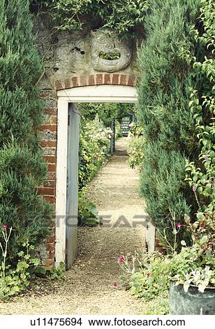 Picture - View of gravel path through door in large walled country garden. Fotosearch