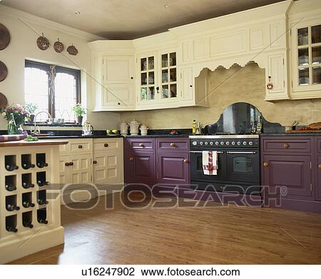 Stock Image - Vinyl wood-effect flooring in kitchen with purple fitted units and cream cupboards. Fotosearch