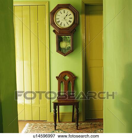 Wall-clock above wooden chair in pastel green cottage hall View Large Photo Image Stock Photo - Wall-clock above wooden chair in pastel green cottage hall. Fotosearch