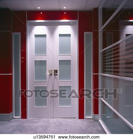 Stock Image - White and blue panelled door in modern red and white hall. Fotosearch