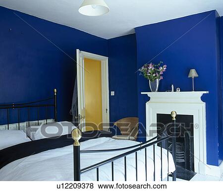 White bedlinen on brass bed in blue bedroom with white fireplace View Large Photo Image Stock Photo - White bedlinen on brass bed in blue bedroom with white fireplace. Fotosearch