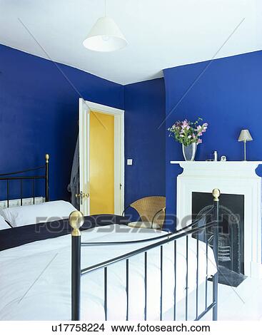White bedlinen on brass bed in bright blue bedroom with white fireplace View Large Photo Image Picture - White bedlinen on brass bed in bright blue bedroom with white fireplace. Fotosearch