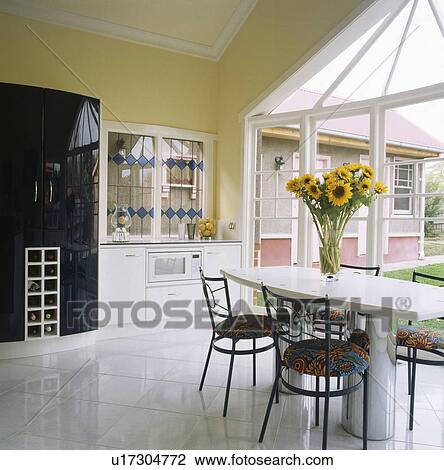Stock Image - White ceramic floor tiles in modern kitchen with floral upholstered chairs. Fotosearch