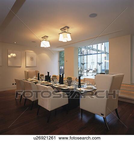 Stock Image - White chairs at table in modern white dining room. Fotosearch