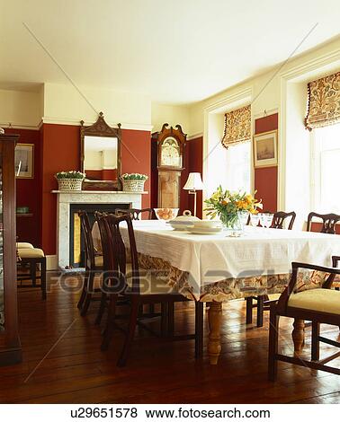 Stock Photo - White cloth on table in red dining room with wooden flooring. Fotosearch