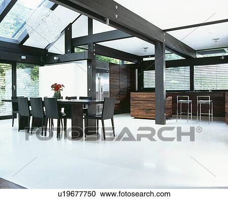Stock Image - White flooring in large white dining room with black table and chairs. Fotosearch