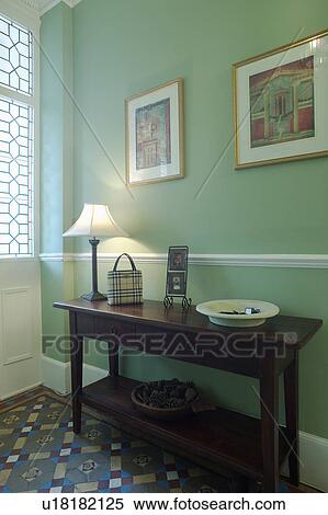 Stock Photography - White lamp on console table in green hall with tessellated floor tiles. Fotosearch