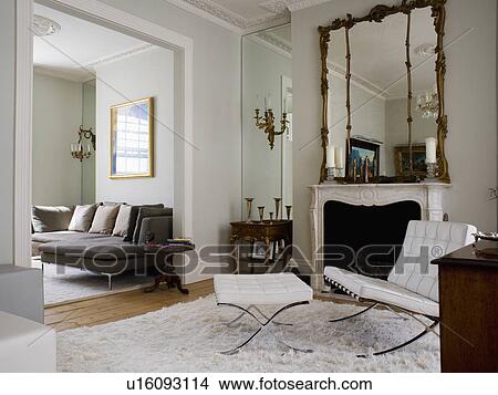 White leather Mies van der Rohe chair and stool in living room with mirrored alcove and antique mirror above fireplace View Large Photo Image Picture - White leather Mies van der Rohe chair and stool in living room with mirrored alcove and antique mirror above fireplace. Fotosearch
