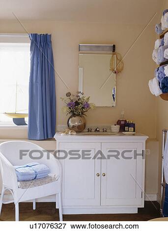 White Lloyd Loom chair beside white vanity unit in peach bathroom View Large Photo Image Stock Photo - White Lloyd Loom chair beside white vanity unit in peach bathroom. Fotosearch