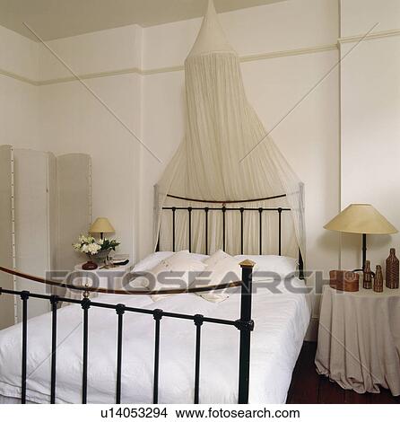 White moxsquito bet above black iron bed with white linen in white bedroom View Large Photo Image Picture - White moxsquito bet above black iron bed with white linen in white bedroom. Fotosearch
