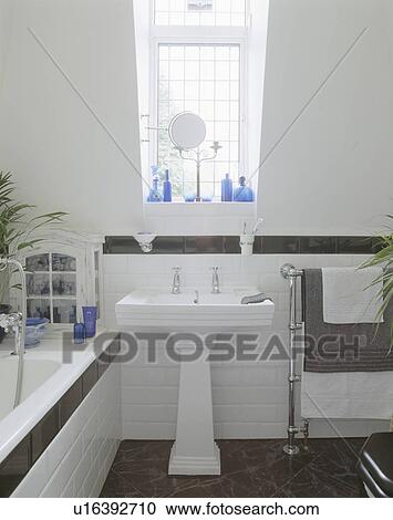 White pedestal basin in modern white bathroom with black tiled dado and heated chrome towelrail View Large Photo Image Stock Image - White pedestal basin in modern white bathroom with black tiled dado and heated chrome towelrail. Fotosearch